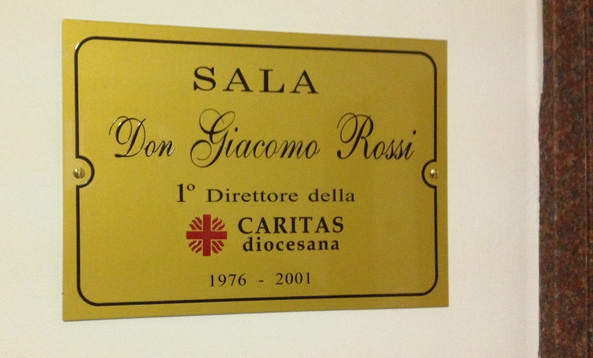 targa allesterno della sala don giacomo rossi del villagg io della carità pg
